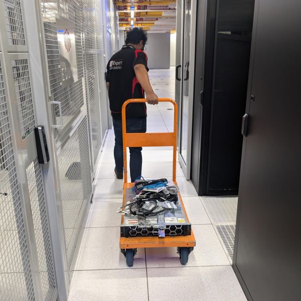 Trucell team member pulling a cart full of hard drives to be used as additional storage for cloud